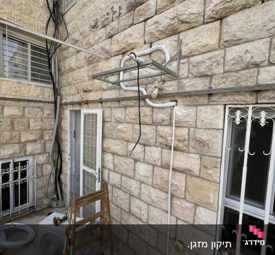 יחידת מזגן חיצונית מותקנת על קיר אבן עם סולם